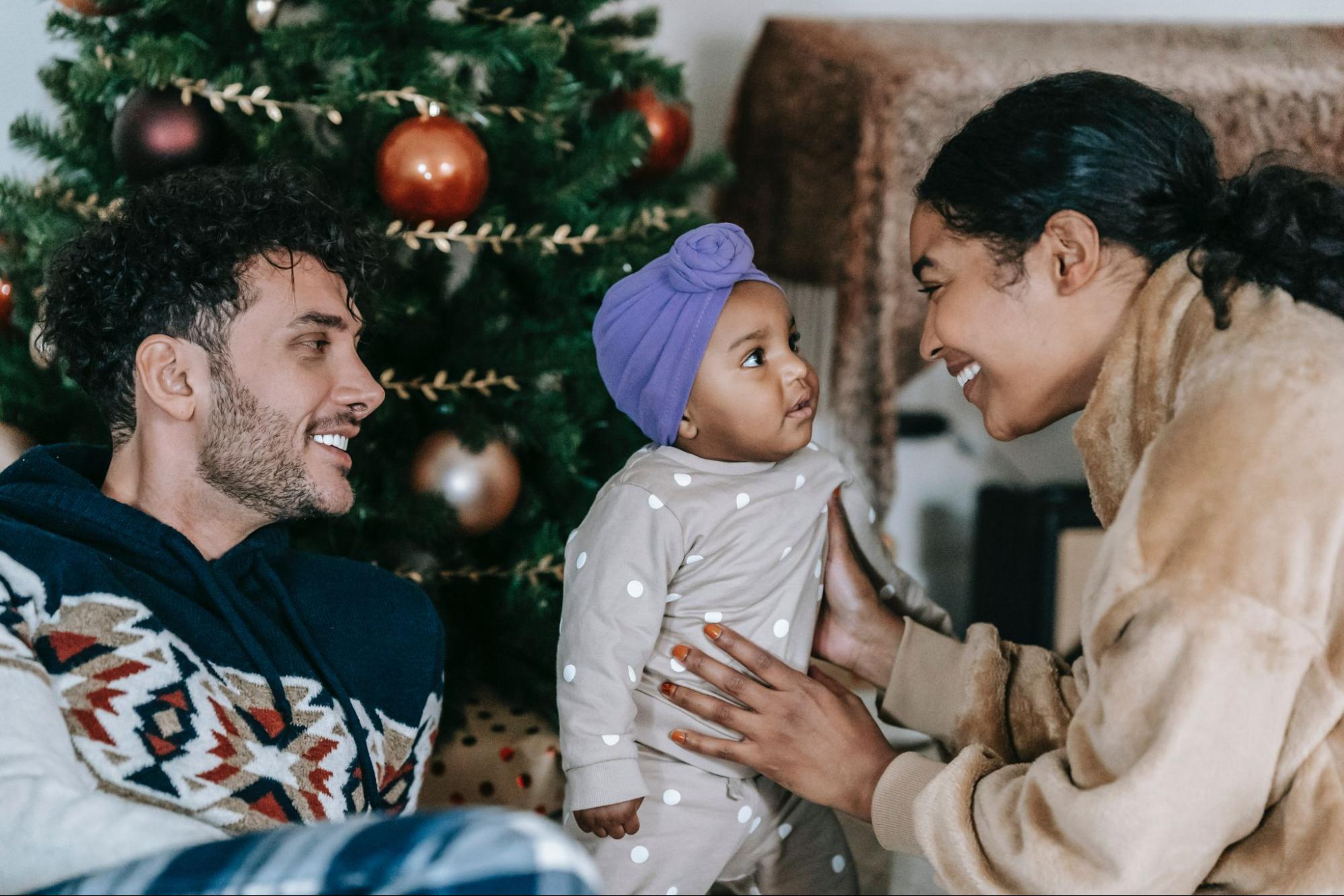 Happy diverse family with baby in front of Christmas tree